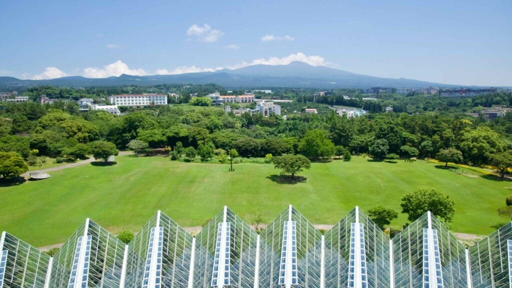 View over Yeomiji’s greenhouse roofs, lawn, and distant hills.
