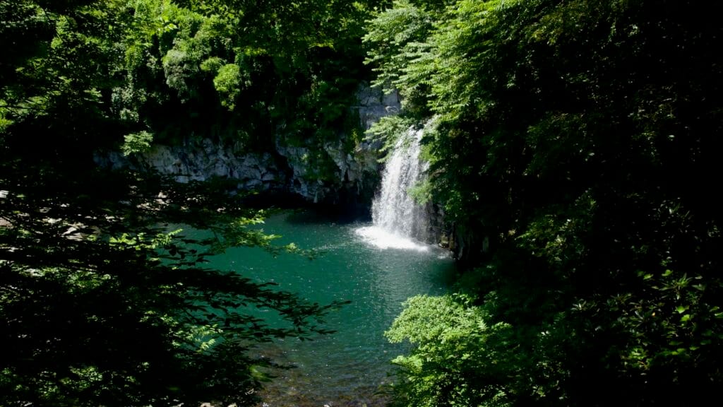 Wide view of Cheonjeyeon’s third waterfall and emerald basin.