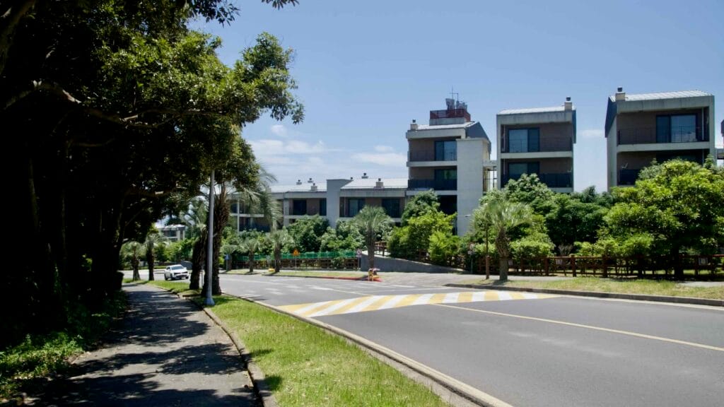 Tree‑lined road past resort residences near the Jungmun coast.