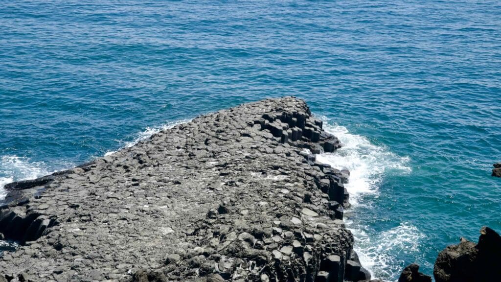 Basalt columns meet the waves of the open sea at Jusangjeolli Cliffs.
