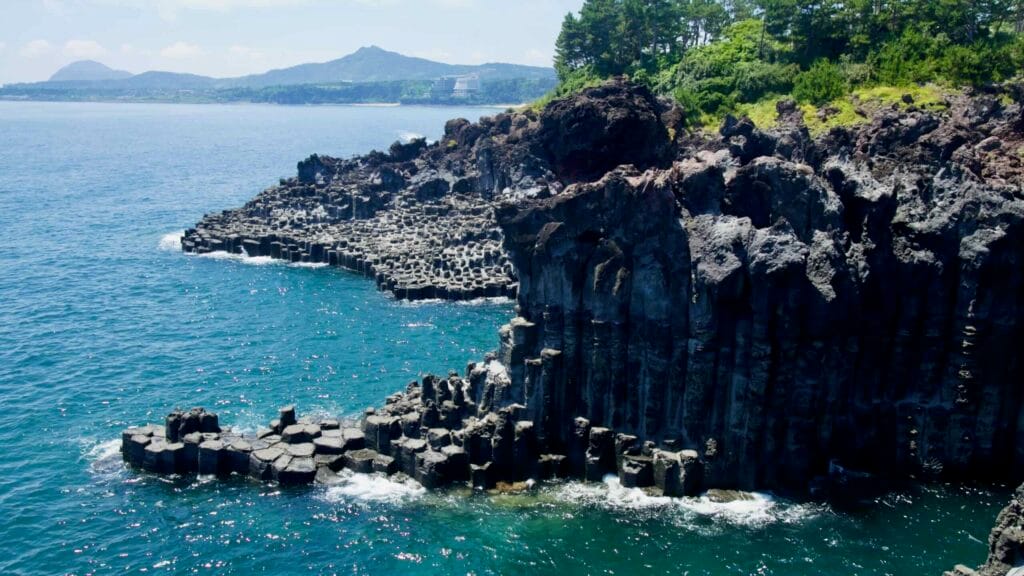 Basalt cliffs at Jusangjeolli with Jeju mountains beyond.