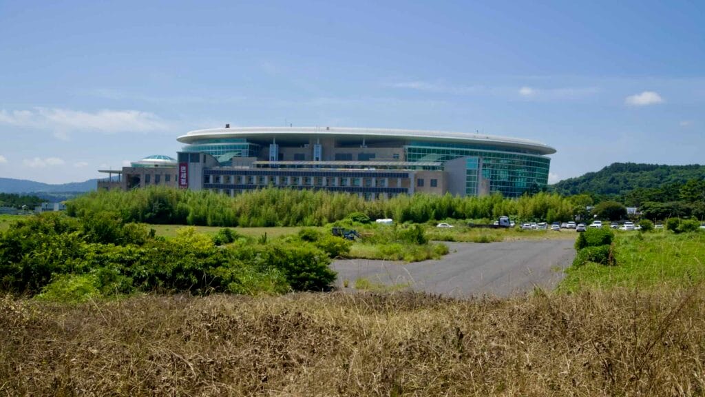 The Jeju World Cup Stadium rises with a modern roof and glass facade in Seogwipo City.