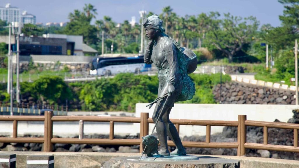 A bronze haenyeo statue stands on a rock at Jamnyeo Square.