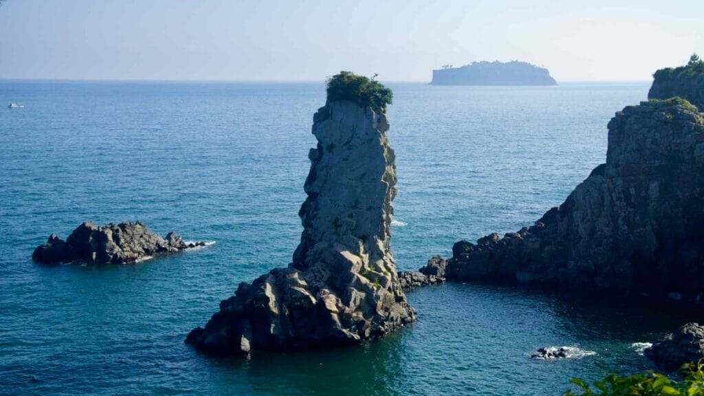Oedolgae Rock rises sharply from the sea, topped with greenery.
