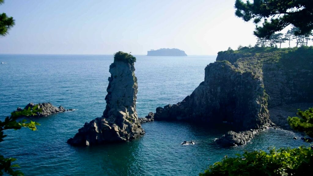 Oedolgae Rock rises near coastal cliffs with Bomsom Island offshore.