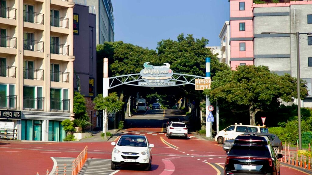 The Arang Joeul gateway marks Seogwipo’s dining street with hotels and traffic around the arch.