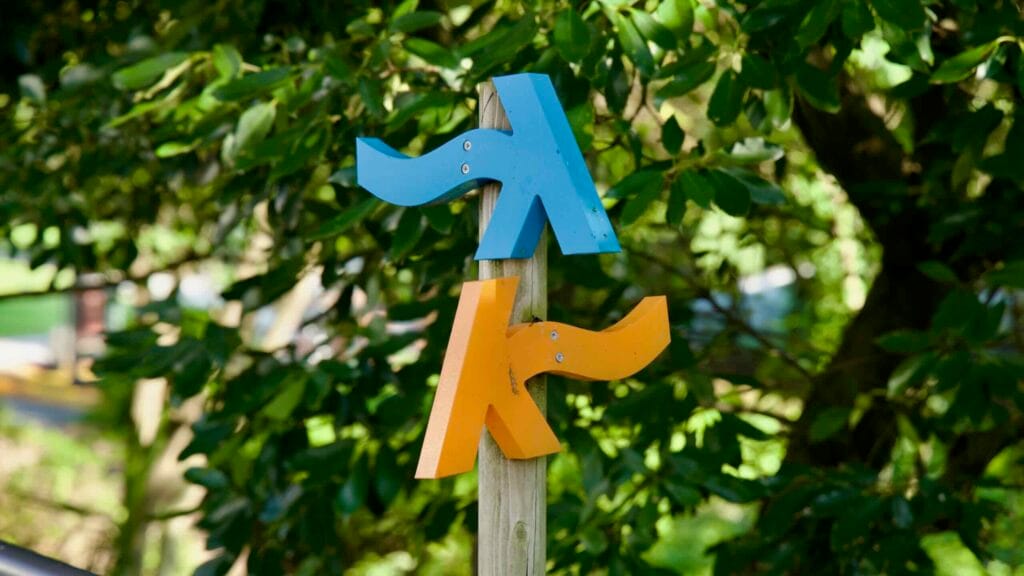 K‑shaped wayfinding arrows stand among trees in Chilsimni Park in downtown Seogwipo.