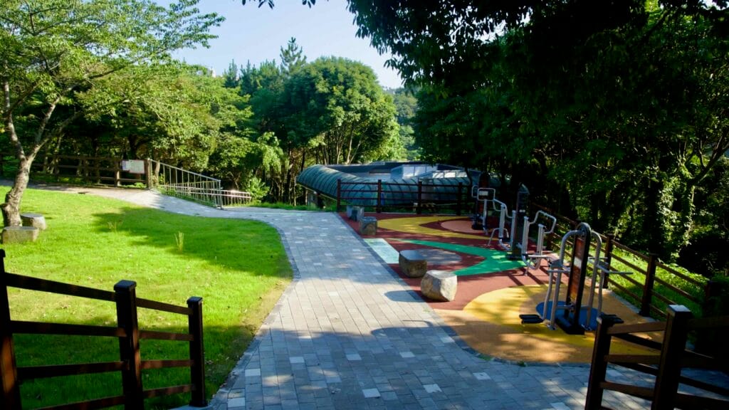 An outdoor gym and shaded path provide a quiet recreation corner in Chilsimni Park.