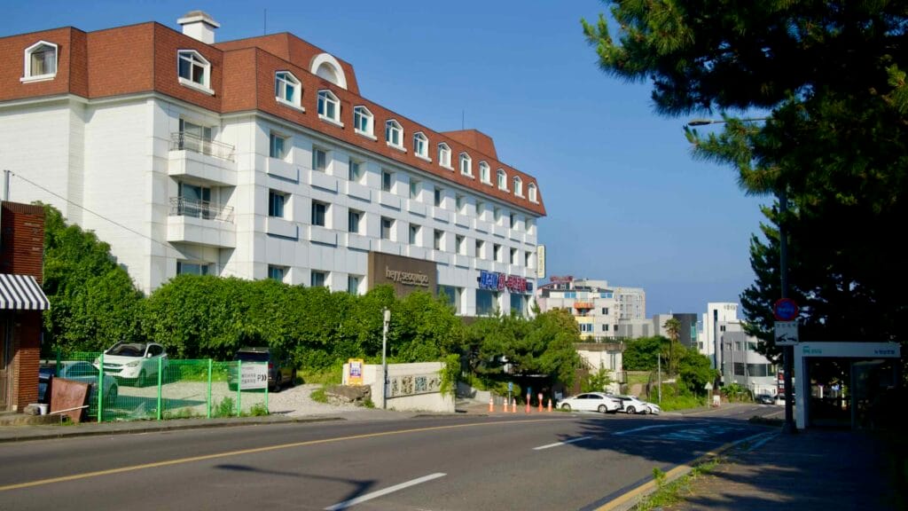 Heyy Seogwipo hotel faces an uphill avenue with trees and small shops on the edge of downtown.