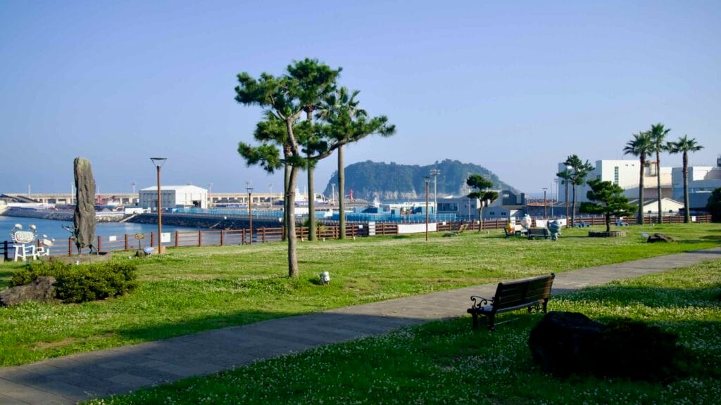 A green lawn in Jaguri Culture & Arts Park overlooks the harbor with Seopseom Island offshore.