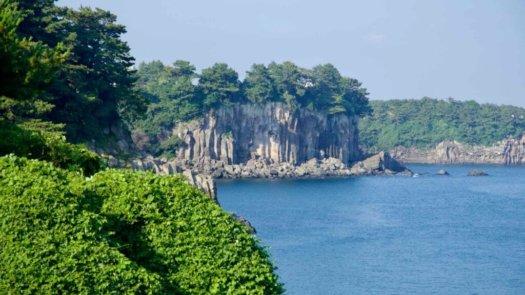 Columnar basalt cliffs line the Jaguri coast near the Jeongbang Falls area in Seogwipo.
