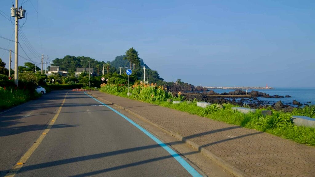 A coastal bike lane follows the shore toward Gudumi Port.