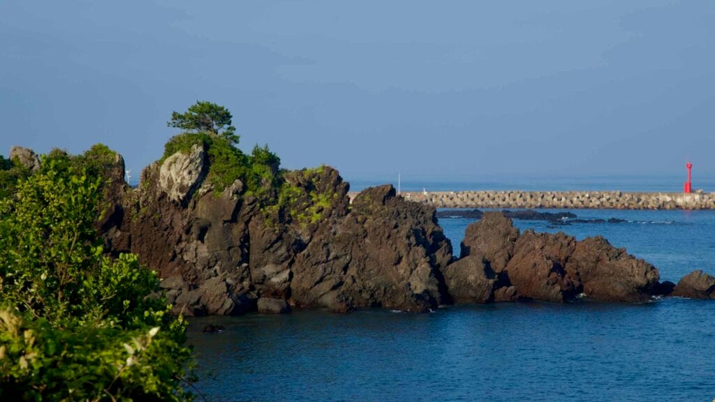 Volcanic crags and a lone pine sit near Gudumi’s lighthouse.