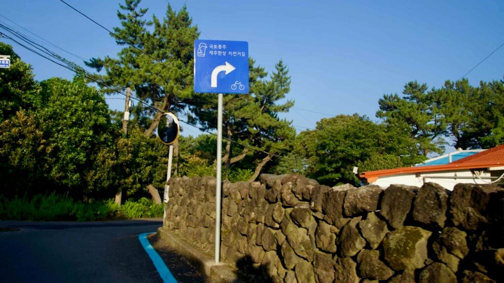 A cycling route sign points along a stone‑walled lane.