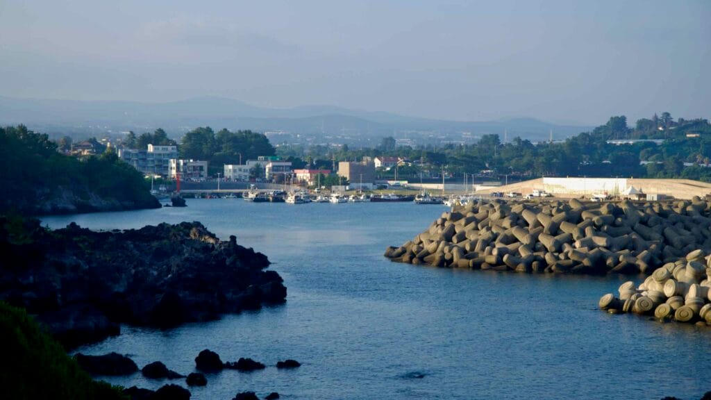 Fishing boats rest inside Hahyo Port as a red harbor light marks the entrance.
