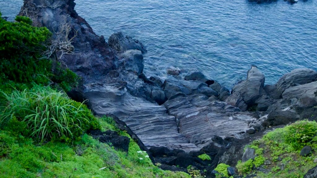 Rippled basalt slabs drop to clear water on Jeju’s south coast.