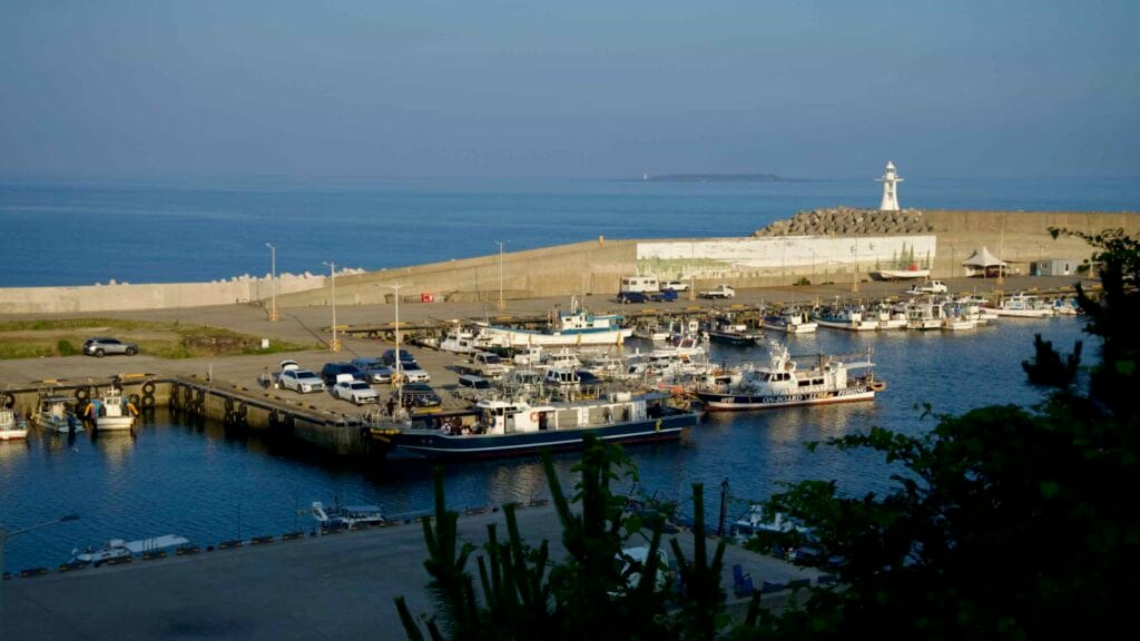 Fishing boats line the quay inside Hahyo Port below the white breakwater light.
