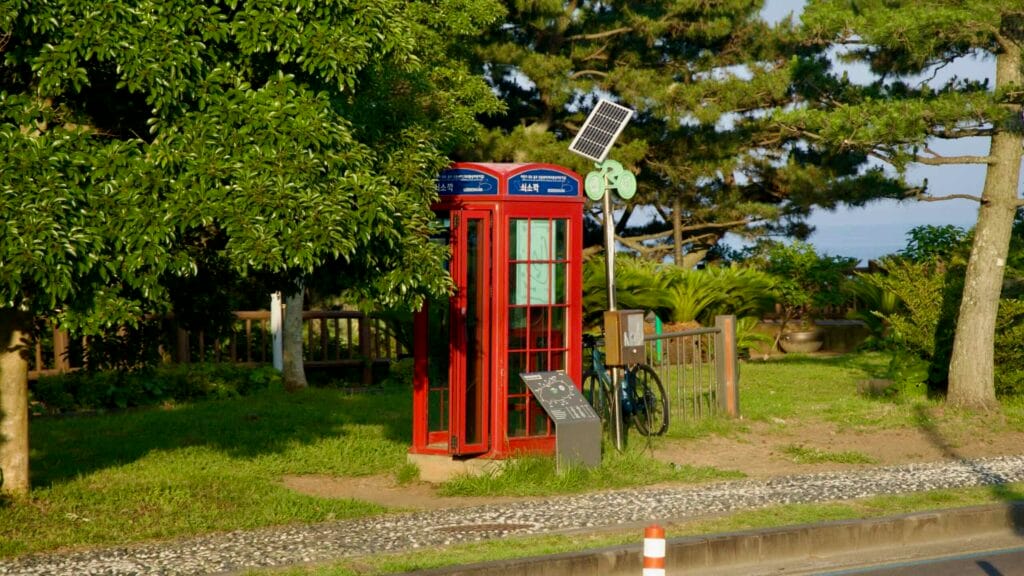 The red certification booth for the Jeju Circular Bicycle Path stands under a solar panel at Soesokkak.