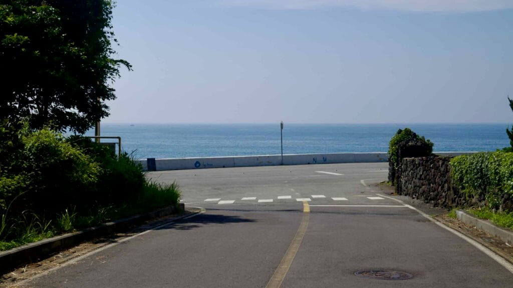 A village street slopes to the seawall near Namwon Port in Seogwipo.