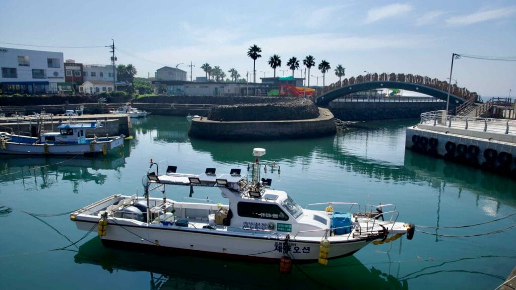 Moored boats sit below an arched bridge and playground at Namwon Port.