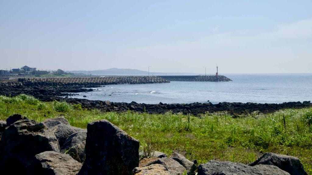 A tetrapod‑lined breakwater and red beacon guard the harbor at Taeheung.