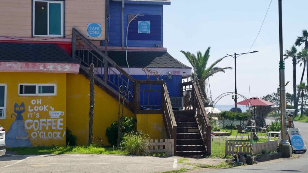 A colorful cafe with outdoor seating stands along the coastal road at Taeheung.