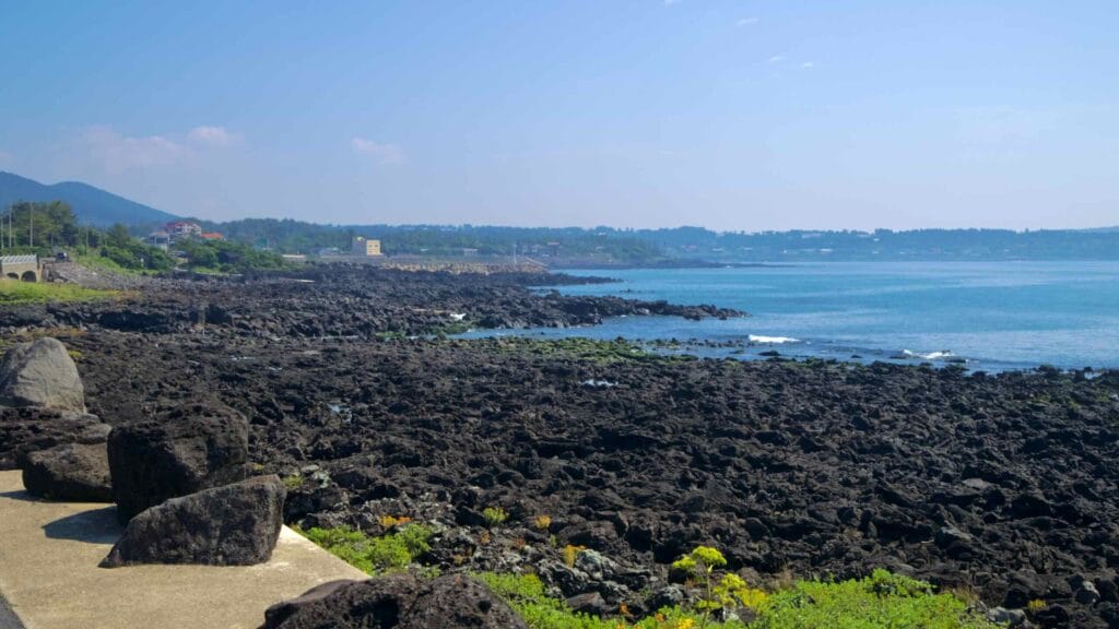 A wide view shows Jeju’s rocky south shore near Taeheung stretching toward villages.