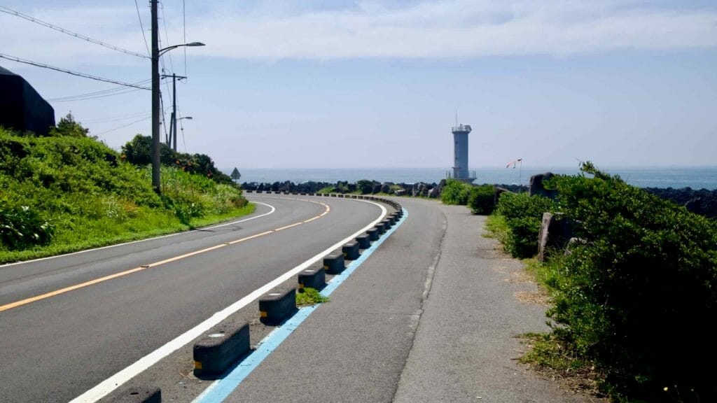 An S-curve in the road approaches a lighthouse near Sinheung-ri.