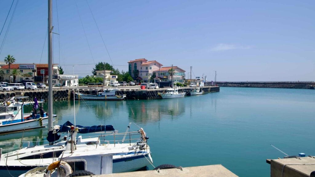 Calm inner basin at Pyoseon Port with moored craft and a long breakwater.