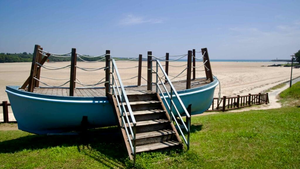 Steps lead up to the boat-shaped viewing deck above Pyoseon Beach sand flats.