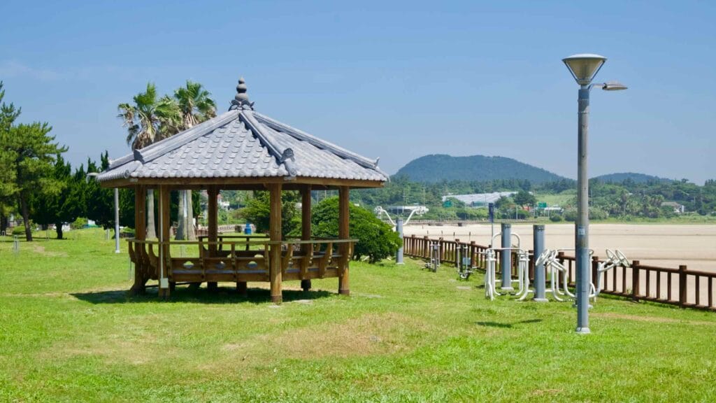 A wooden pavilion stands by outdoor fitness gear beside Pyoseon’s tidal flats.