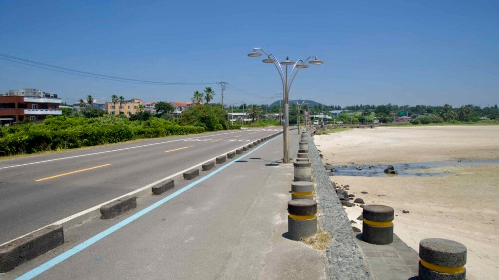 Streetlamps and bollards line the coastal road beside Pyoseon’s tidal flats.