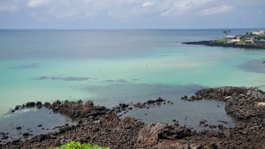 Basalt tide pools and pale green water at Handam Beach’s sheltered bay.