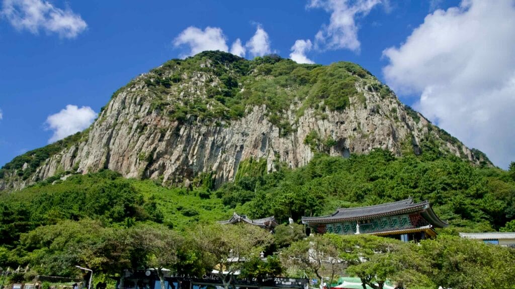 Temple roofs below Sanbangsan volcanic cliffs.