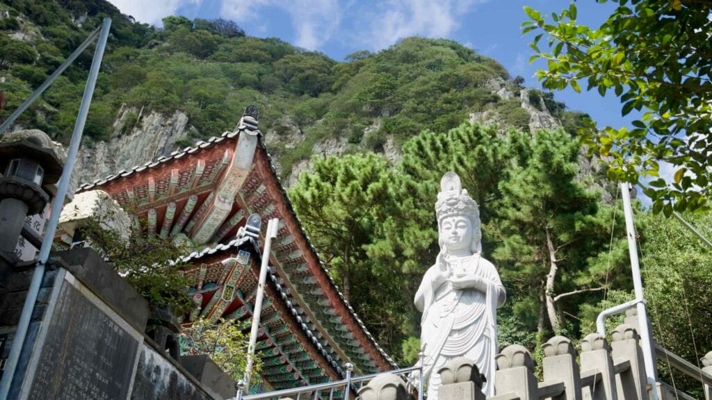 Golden prayer wheels on a terrace railing at Bomunsa Temple on Sanbangsan Mountain, overlooking the sea.
