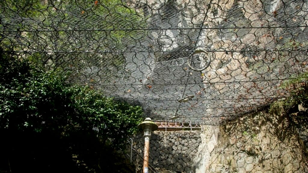 Rockfall netting spans above the Sanbangsan trail, protecting visitors below steep cliffs.