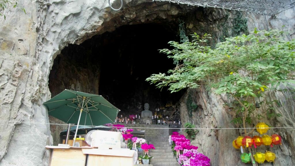 Entrance to Bomunsa’s cave shrine on Sanbangsan, with Buddha, orchids, and stone offerings.