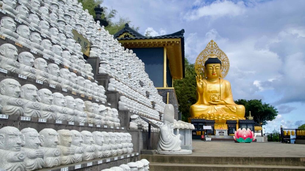 Golden Buddha and rows of white disciple statues at Bomunsa on Sanbangsan overlook the sea.