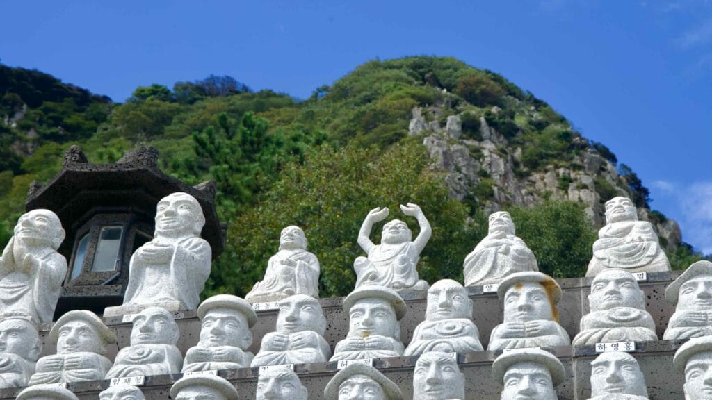 Rows of stone disciple statues, each uniquely carved, line the steps near Bomunsa Temple on Sanbangsan.