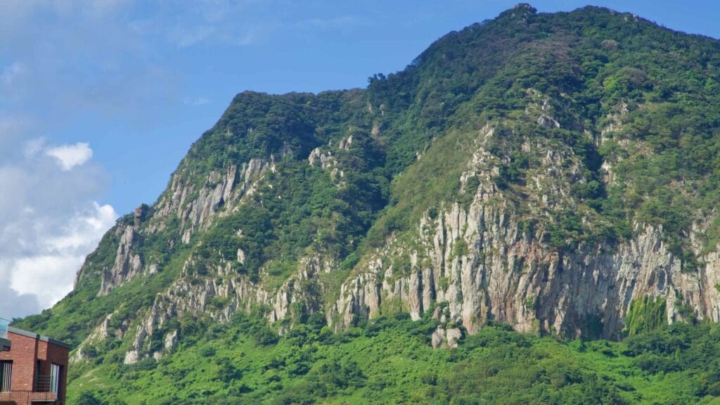 Rugged Yongmeori Coast extends into the sea beneath clouds, with tidal rocks and visitors exploring the shore.