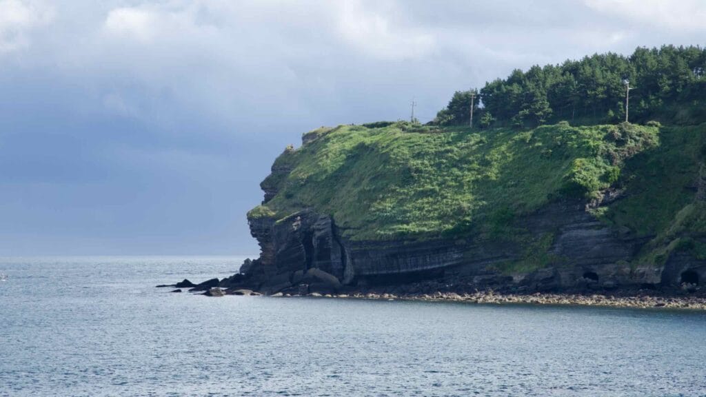 Headland, layered tuff, and sea caves at Songak Mountain.