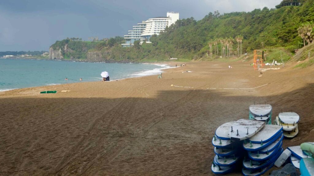 Soft-top surfboards stack on the upper beach after lessons as dark clouds gather offshore by the resort.
