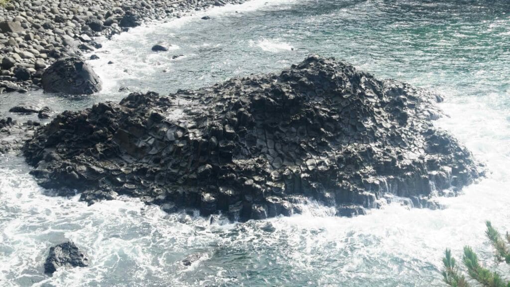 A black basalt outcrop with columnar patterns and waves at Daepo Jusangjeolli Cliff.