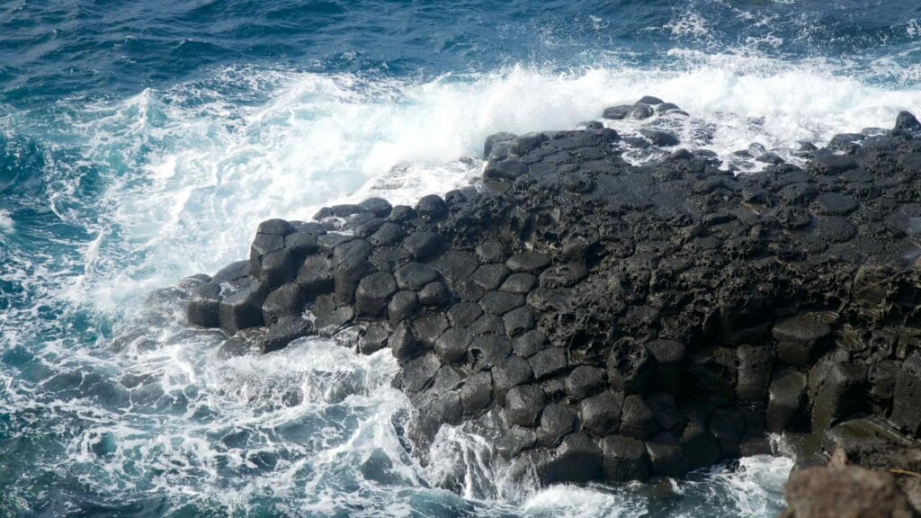 Hexagonal basalt columns meet crashing waves along the Daepo Jusangjeolli coastline in Seogwipo.