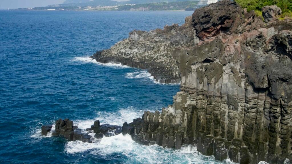 Basalt cliffs and columnar joints stretch into the sea at Daepo Jusangjeolli Cliff.