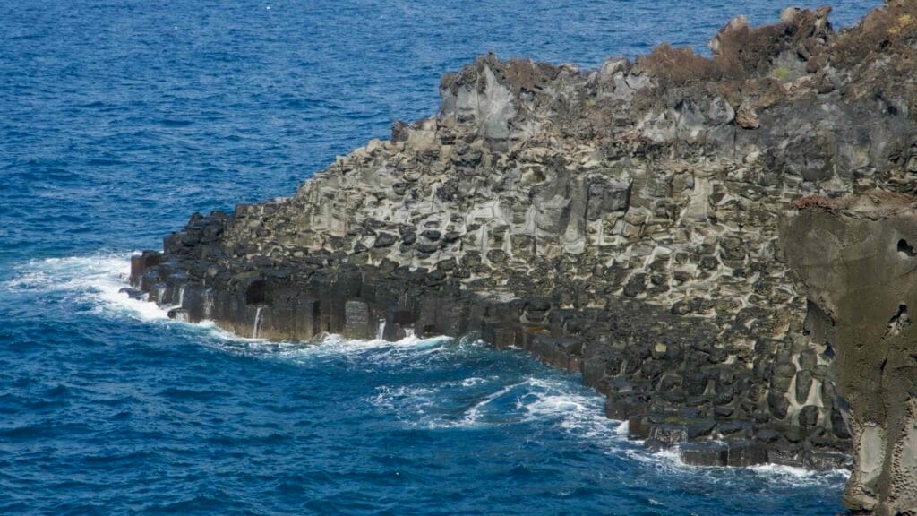 Waves crash against the vertical basalt columns at Daepo Jusangjeolli Cliffs.