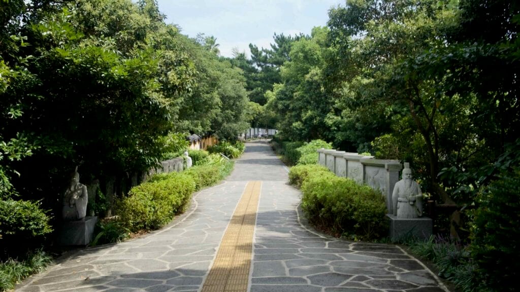 A tree‑shaded stone path leads toward the Jeongbang Falls area.