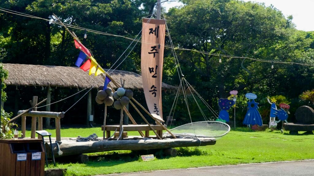 A traditional raft with floats is displayed on the lawn at Jeju Folk Village.