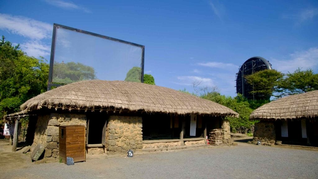 Thatched stone houses surround a yard at Jeju Folk Village.