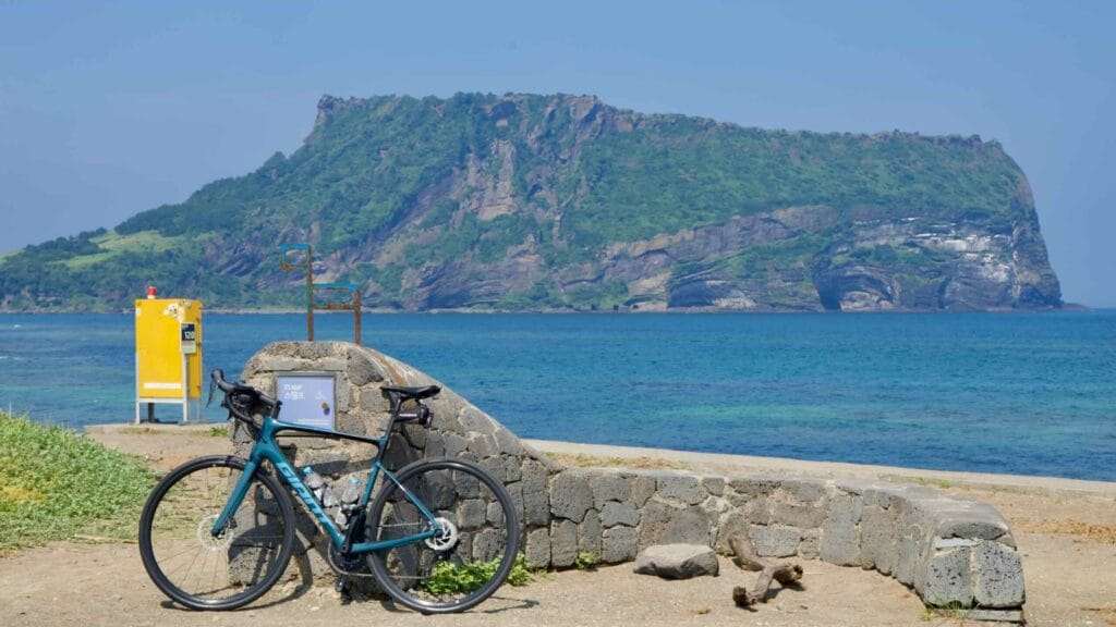 A road bike leans against a stone stamp point along the Jeju cycling route.